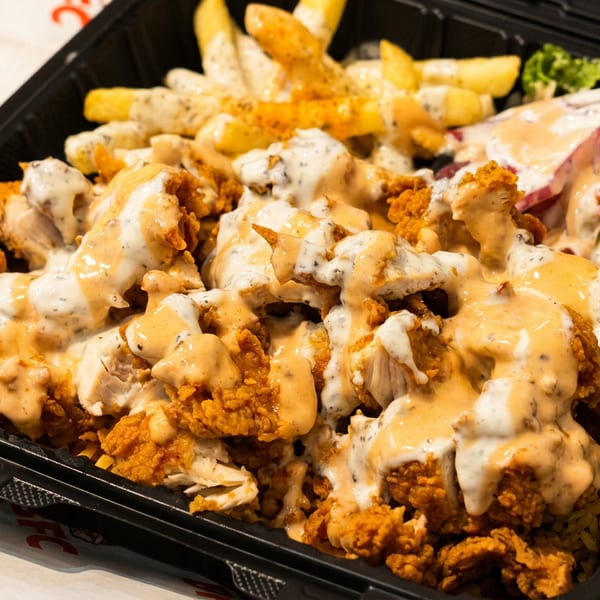 KFC Zinger rice box with crispy chicken, fries, red onions, lettuce, and two sauces.